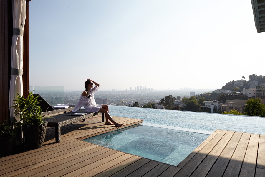 A woman sits by her terrace pool while enjoying the view of the city.
